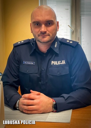 Umundurowany policjant siedzący przy biurku