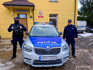 interweniujący policjanci stoją przy radiowozie przed komisariatem