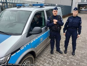 Umundurowany policjant i policjantka stoją przy radiowozie