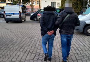 Policjant prowadzi zatrzymanego mężczyznę