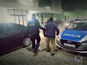 umundurowany policjant prowadzi do komisariatu odnalezionego mężczyznę