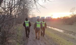 policjanci w trakcie poszukiwań zaginionych dziewczynek  idący wzdłuż zalesionego rejonu