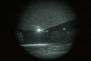 Policyjny śmigłowiec w locie widziany w obiektywie noktowizora.