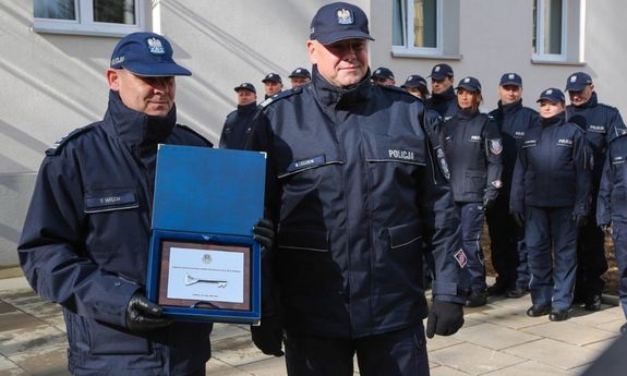 dwóch umundurowanych policjantów, z których jeden trzyma symboliczny klucz