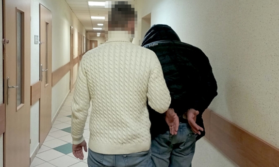 policjant prowadzi zatrzymanego mężczyznę korytarzem