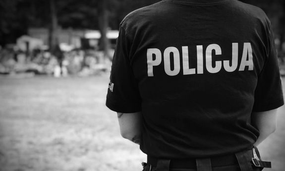 widok na plecy policjanta, który ma na sobie koszulkę z napisem Policja
