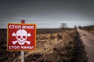 tablica informacyjna stojąca na skraju drogi w języku ukraińskim informująca o zaminowanym terenie