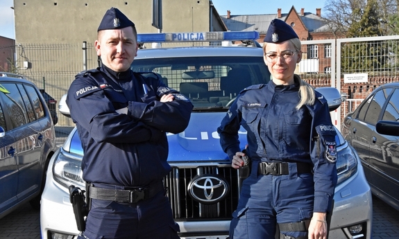 umundurowana policjantka i policjant stoją przy radiowozie