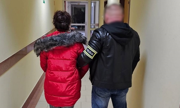 policjant prowadzi zatrzymaną kobietę