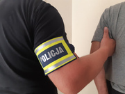 policjant ubrany po cywilnemu prowadzi zatrzymanego