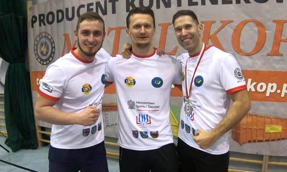 trzej katowiccy policjanci pozują do zdjęcia na tle reklamy jednego ze sponsorów