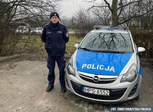 umundurowany policjant stoi przy radiowozie