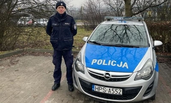 umundurowany policjant stoi przy radiowozie