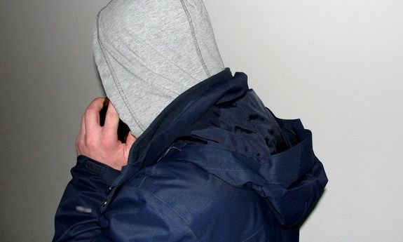 mężczyzna w bluzie w kapturem na głowie rozmawia przez telefon komórkowy