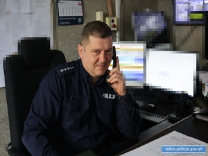 w pomieszczeniu policjant ze słuchawką telefoniczną przy uchu