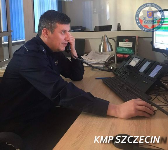 umundurowany policjant siedzi przy biurku i rozmawia przez telefon