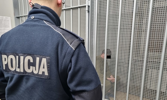 umundurowany stoi przed pomieszczeniem dla osób zatrzymanych