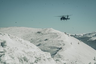 Policyjny Black Hawk w zawisie. Za pomocą dwóch lin desantowych uczestnicy szkolenia opuszczają się na pokryte śniegiem zbocze górskie.
