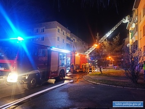 Na zdjęciu dwa wozy strażackie gaszące pożar w bloku