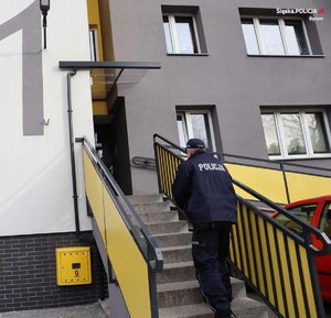 umundurowany policjant wchodzi po schodach do budynku