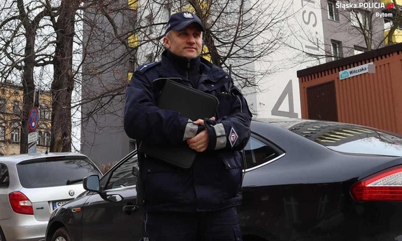 umundurowany policjant stoi przy samochodzie