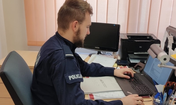 umundurowany policjant siedzi przy biurku