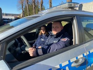 policjant i policjantka w radiowozie - widok z boku przez opuszczona szybę auta