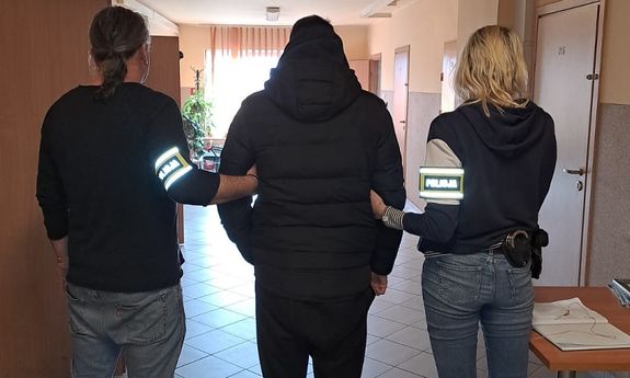 Policjanci prowadzą podejrzanego korytarzem