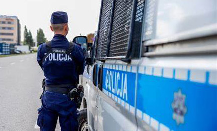 umundurowany policjant stojący przy policyjnym radiowozie