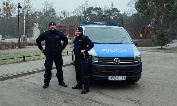 dwaj policjanci stojący przy radiowozie