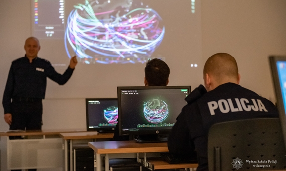 policjanci siedzą w ławkach, przed nimi stoi funkcjonariusz prowadzący kurs specjalistyczny