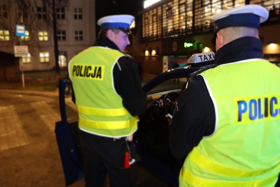 dwaj policjanci kontrolują kierowcę auta