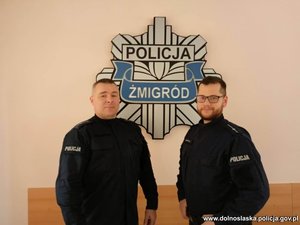 Dwóch policjantów w mundurach stojących przed gwiazdą policyjną z napisem Żmigród