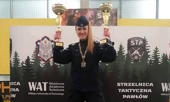 sierżant Agnieszka Jeż stoi na podium trzymając w górze dwa puchary