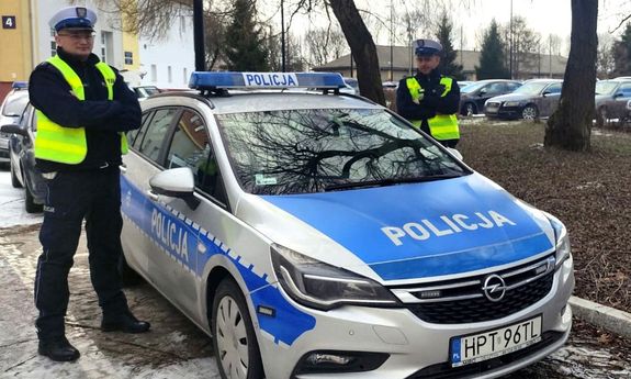 dwaj policjanci, mł. asp. Janusz Metera i st. post. Karol Wróblewski stoją przy radiowozie