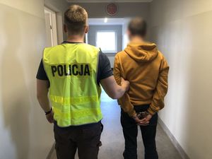 policjant z zatrzymanym mężczyzną zakutym w kajdanki