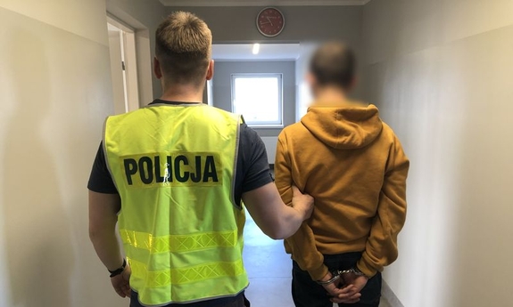 policjant z zatrzymanym mężczyzną zakutym w kajdanki