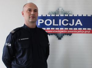 policjant sierż. szt. Dawid Sosnowski stoi na tle policyjnego baneru