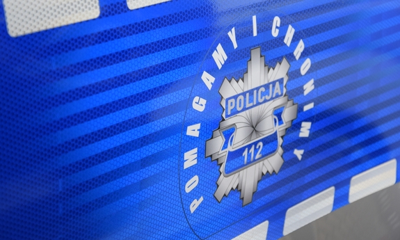 Na zdjęciu logo policji z napisem pomagamy i chronimy na drzwiach radiowozu