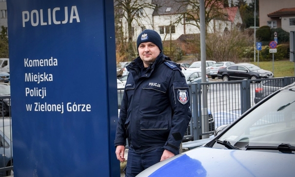 Umundurowany policjant stojący przy radiowozie