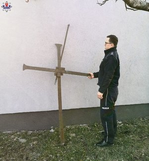 policjant stoi przy odzyskanym krzyżu