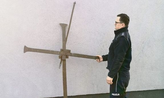 policjant stoi przy odzyskanym krzyżu
