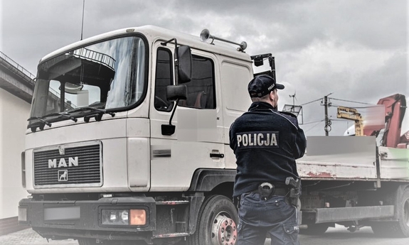 samochód ciężarowy, który brał udział w kolizji i stojący przy nim policjant
