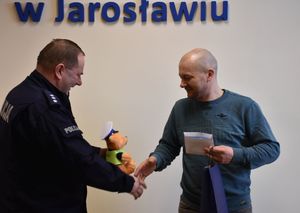 Policjant wręcza mężczyźnie policyjnego misia
