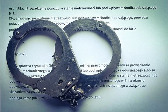 kajdanki leżą na kartce z zapisanymi paragrafami