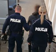 umundurowana policjantka i policjant prowadzą zatrzymanego - widok z tyłu