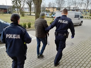 dwoje umundurowanych policjantów prowadzi zatrzymanego