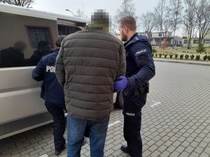 dwoje umundurowanych policjantów prowadzi zatrzymanego