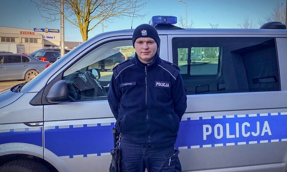 policjant stoi przed radiowozem policyjnym