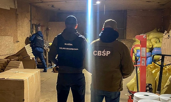policjant i funkcjonariusz służby celno-skarbowej w trakcie oględzin magazynu